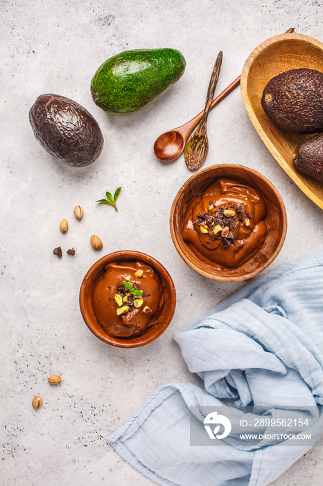 Avocado chocolate mousse with pistachios in wooden bowl on white background.