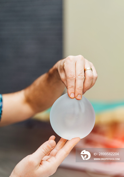 Plastic surgery silicone sample in hands. Implant round silicone sample.