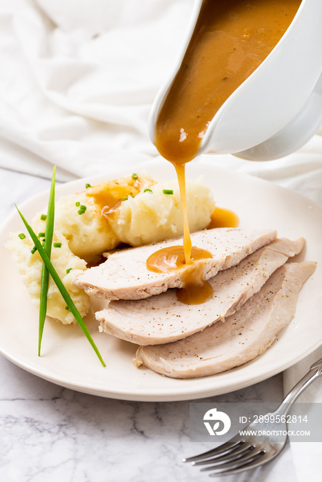 pouring gravy over meat on a thanksgiving meal