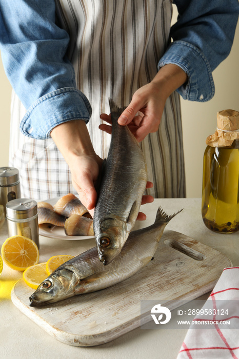Concept of cooking fish with woman hold fresh herring fish