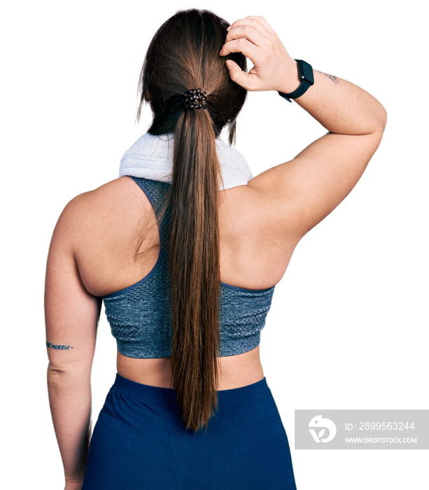 Young hispanic girl wearing sportswear and towel backwards thinking about doubt with hand on head