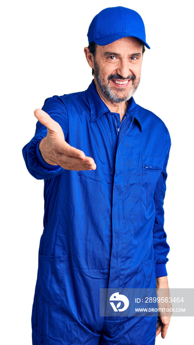 Middle age handsome man wearing mechanic uniform smiling cheerful offering palm hand giving assistance and acceptance.