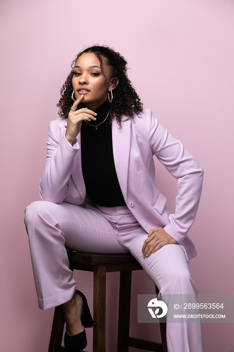 Editorial portrait of a confident young black successful business woman in a pink studio