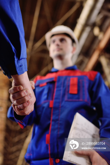 Strong handshake of men in overalls of industrial workers