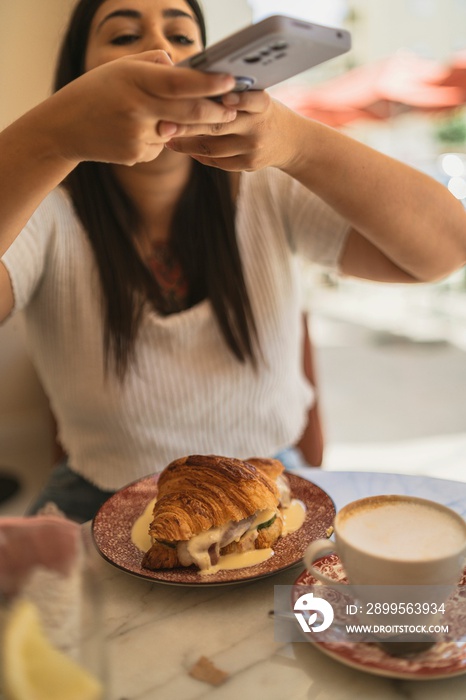 Vertical closeup of a young woman taking photos of her delicious lunch