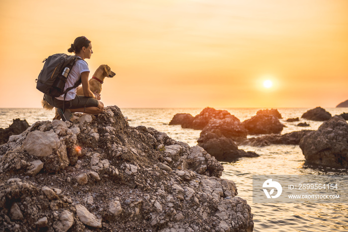 Woman with a dog hiking along the seashore