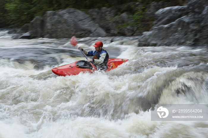 Side view of a man kayaking in rough river