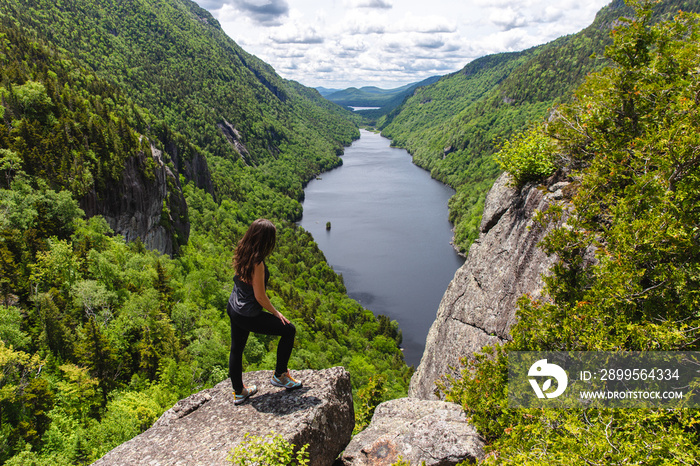 girl standing in front of a valley with green trees and a lake