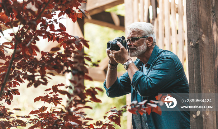 A mature man with a beard and a camera takes pictures, paparazzi. Retired active hobby, senior journalist.