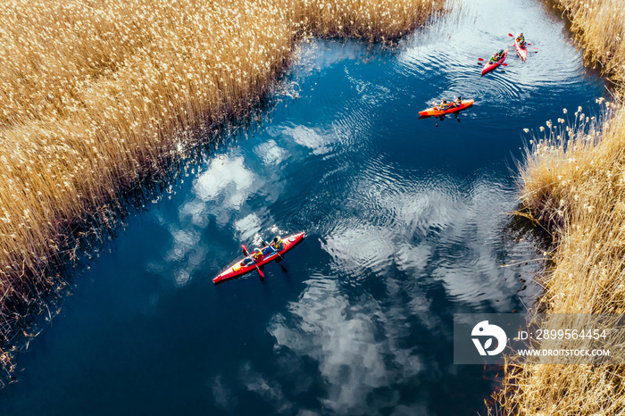 Group of people in kayaks among reeds on the autumn river.