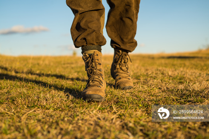 travel adventure. future. military shoes. male feet in green boots. hynter searching for victim in grass field. going to success. freedom. soldier uniform. step up. walking. hiking and camping