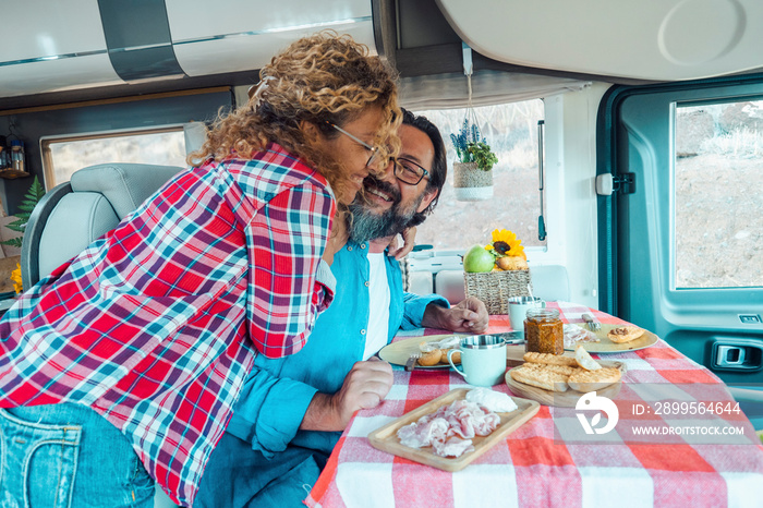 Happy traveler couple hug with love and fun together inside a camper van motor home. People using rv vehicle for travel and enjoy holiday vacation on the road. Van life off grid lifestyle caucasian