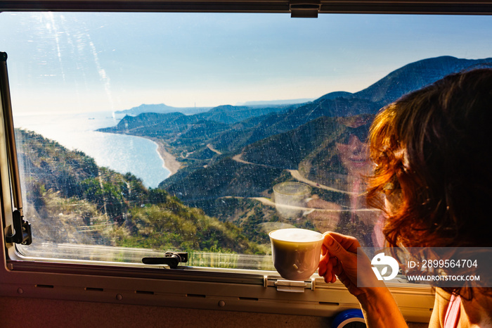 Woman in rv enjoy coast view, drinking coffee