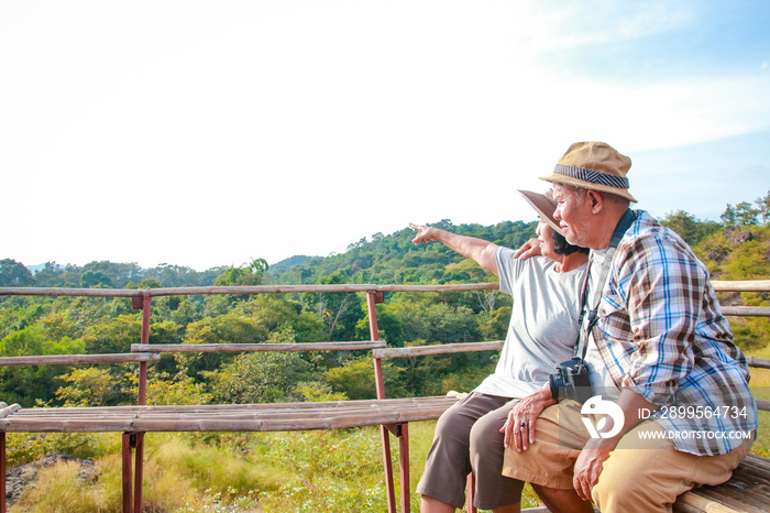 Asian elderly couple enjoying traveling Sit on the mountain looking at the beautiful natural scenery. Tourism concept. healthy. Happy living in retirement. Copy space