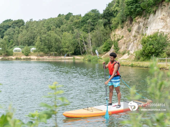 Young paddleboarding on lake