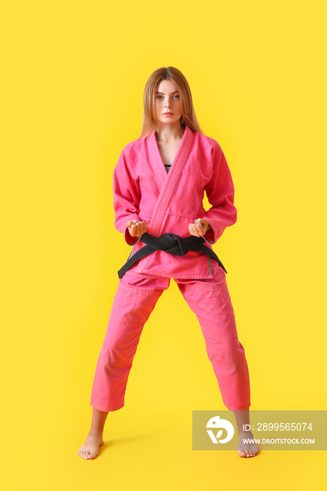 Young woman practicing karate on color background