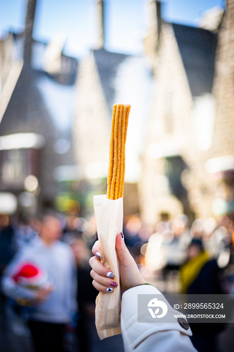 Churros stick - the traditional Spain dessert in hand holding with background copy space.