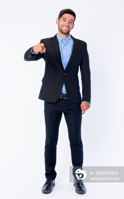 Full body shot of happy young bearded Persian businessman pointing at camera