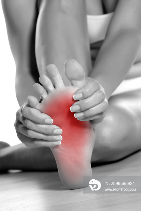 woman massaging her painful foot on white background