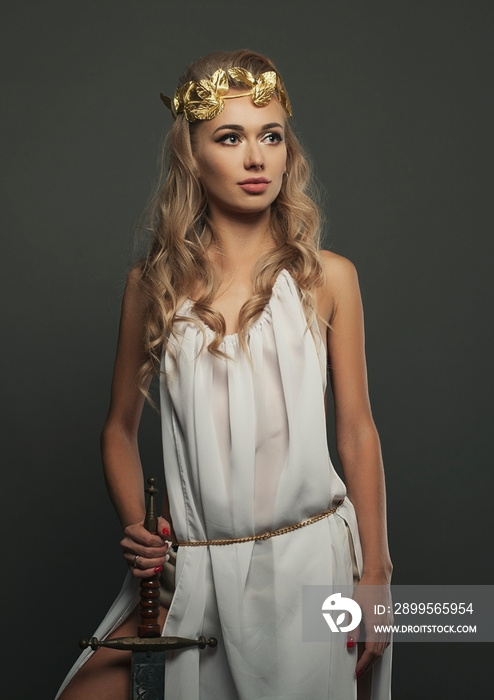 goddess young woman with sword on dark bg studio shot