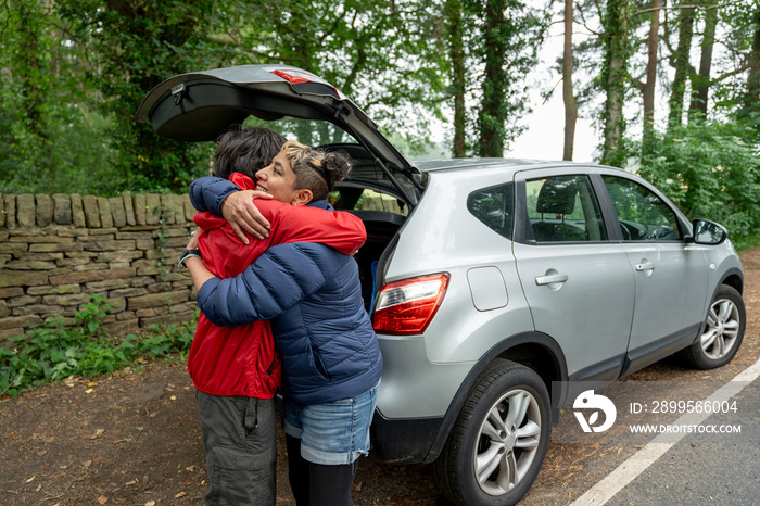 Mother and son hugging by car after hike