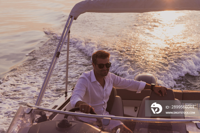 A determined senior businessman in casual clothes and sunglasses enjoys his vacation driving a luxury boat at sunset. Selective focus