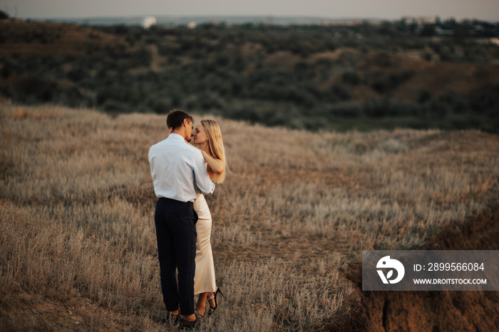 Beautiful couple in love embracing with closed eyes. Happy blonde girl whispering about love.