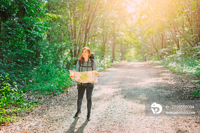 Traveling Happy Asian woman with backpack walking on path the tropical forest looking at the camera and map in green rainforests. Summer holiday and vacation trip , Survival travel, lifestyle concept