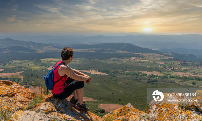 Girl with blue backpack and sport clothes, enjoying from the mountain valley in magical moments.