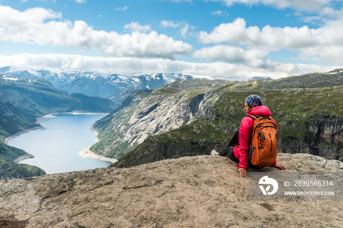 Sporty woman posing on Trolltunga. Happy hiker enjoy beautiful lake and good weather in Norway.