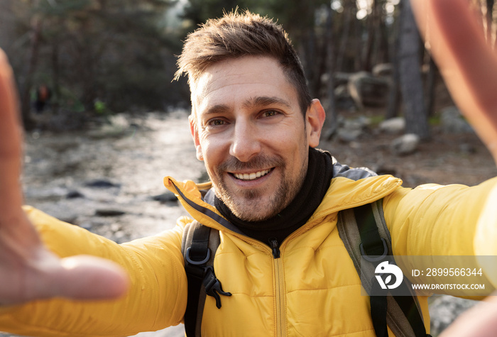 Young hiker taking selfie portrait in the forest, happy guy smiling at camera Hiking and climbing cliff