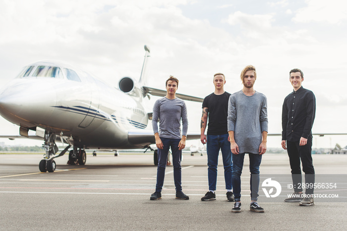 Four friends waiting for take-off near plane