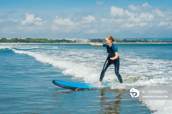 Joyful young woman beginner surfer with blue surf has fun on small sea waves. Active family lifestyle, people outdoor water sport lesson and swimming activity on surf camp summer vacation