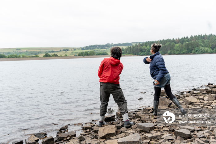 Mother and son skipping stones in lake