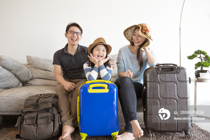 Happy Asian family is preparing for travel at home .Mom daughter and father are packing suitcases for the trip.