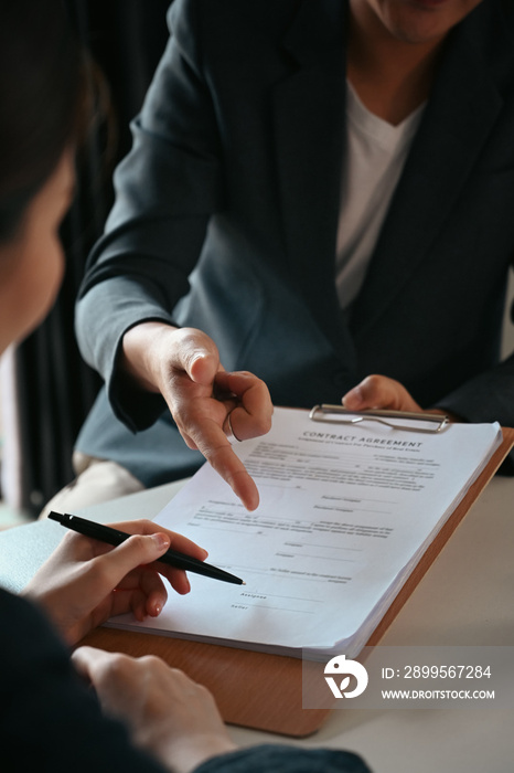 Cropped shot of businesswoman signing agreement with skilled lawyer on wooden table