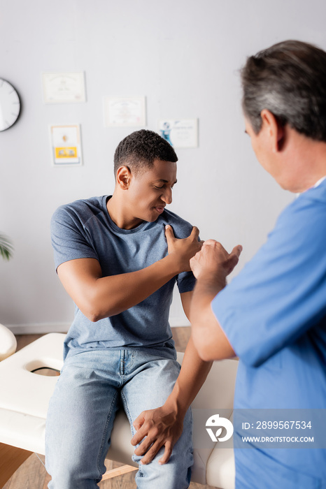 blurred doctor pointing at injured arm of african american patient