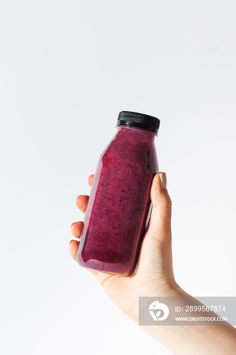 Berry smoothie in a bottle in the hand of a woman. Detox, healthy eating. Copy space.