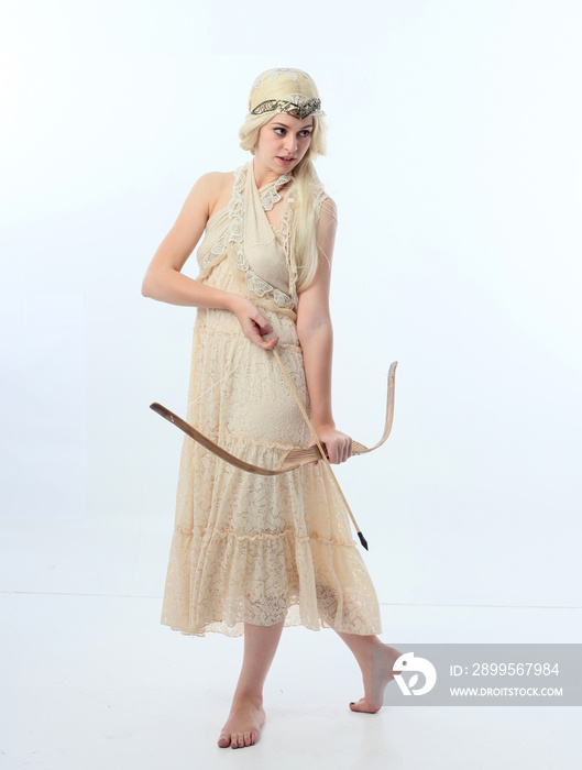 Full length portrait of pretty female model wearing  grecian goddess  toga gown, posing with elegant gestural movements on a studio background.