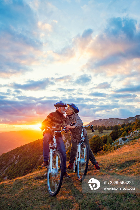 Active Senior Couple on country bike ride. Kissing on their break.