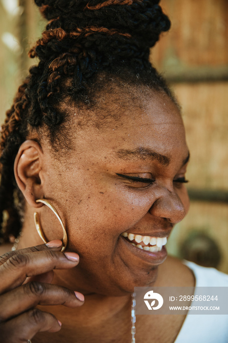 closeup portrait of a plus size afro latinx haitian american holding gold earring smiling