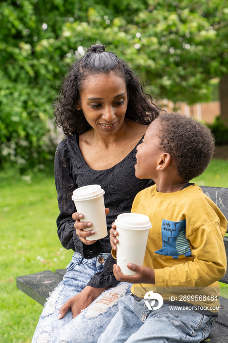 Mother and son sitting on bench in park