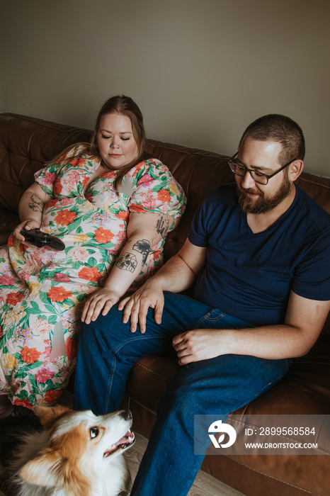 couple sits on couch and watches dog