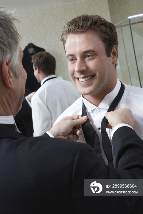 Father tying young groom’s bow tie