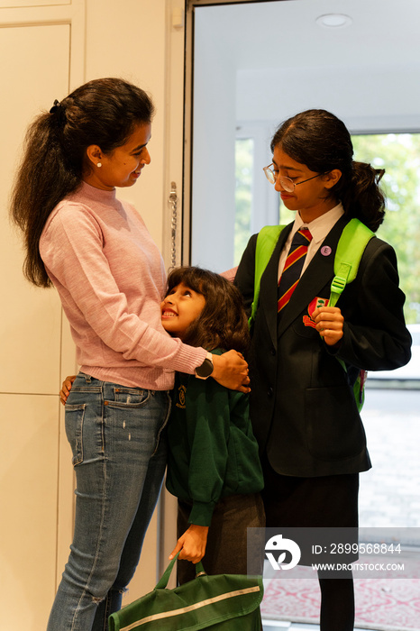 Mother greeting daughters after returning from school