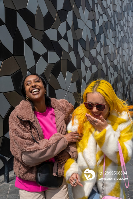 Stylish young friends laughing outdoors