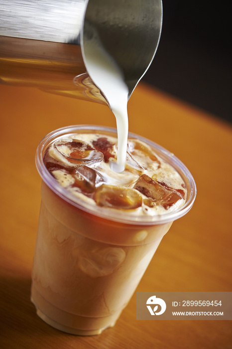 Pouring milk in iced caramel latte