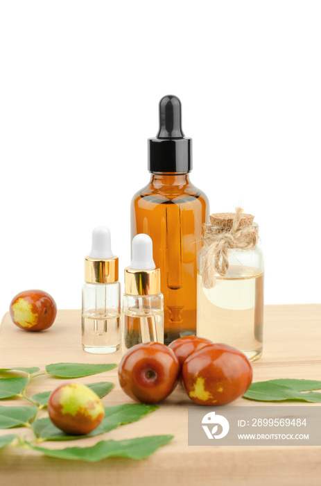 Jojoba oil in a bottle with a dropper and fresh jojoba fruit