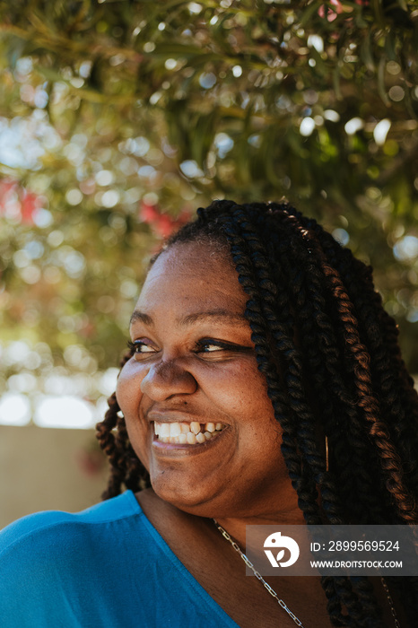 closeup plus size Afro Latinx Haitian American woman smiling under flowering tree looking away