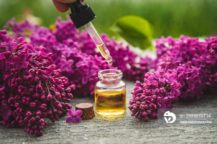 Lilac essential oil in a small bottle. Selective focus.